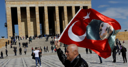 Seorang pria mengibarkan bendera Turki dengan potret Mustafa Kemal Ataturk di depan Anitkabir, tempat peristirahatan Ataturk, di Ankara, Turki, Selasa (2/4/2019)./Reuters-Umit Bektas
