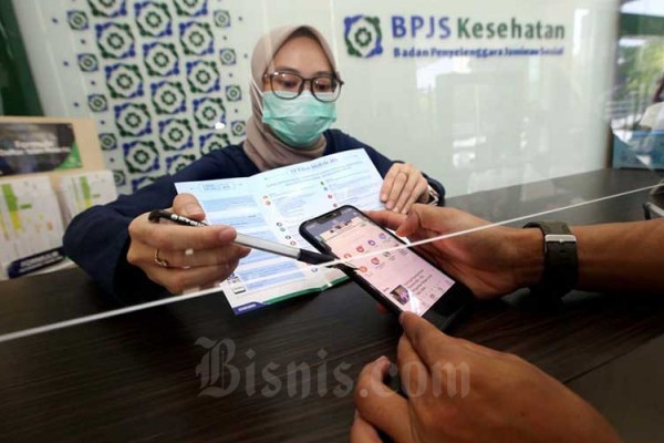 Petugas menjelaskan kepada peserta tentang fitur-fitur yang ada di aplikasi Mobile JKN di Kantor BPJS Kesehatan Cabang Bandung, Jawa Barat, Kamis (13/8/2020). Bisnis/Rachman