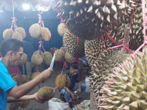 Penjual durian di Pasar Kuto Palembang memilih buah kepada pelanggan./Bisnis.com-Abdurachman