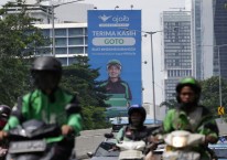 Pengendara sepeda motor melintasi papan reklame Ajaib Sekuritas yang mengiklankan penawaran umum perdana GOTO di Jakarta. - Bloomberg/Dimas Ardian