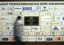Karyawan beraktifitas di dekat deretan logo-logo perusahaan asuransi di Kantor Asosiasi Asuransi Umum Indonesia (AAUI) di Jakarta. Bisnis/Himawan L Nugraha