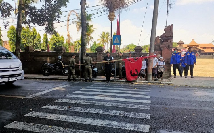 Petugas Satpol PP melakukan pencopotan bendera partai PDIP di Gianyar, Bali.