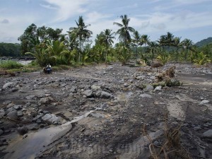 Sejumlah warga melintasi lahan pertanian yang tertimbun material banjir di Pasirian, Lumajang, Jawa Timur, Selasa (23/4/2024).