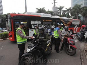 Anggota Kepolisian Korps Lalu lintas melakukan penindakan tilang manual di Bundaran HI, Jalan Imam Bonjol, Jakarta, Jumat (26/4/2024).