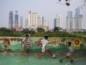 Sejumlah anak bermain sepak bola dengan latar belakang gedung bertingkat di kawasan Petamburan, Jakarta, Minggu (5/5/2024).