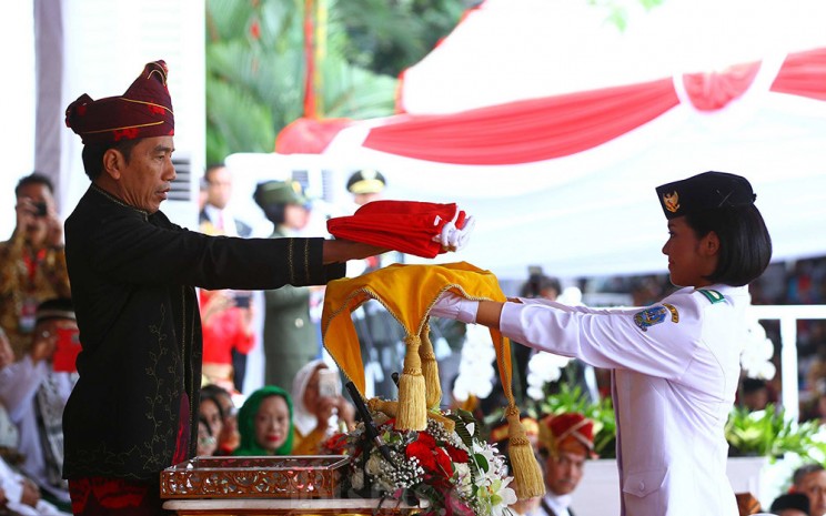 Presiden Joko Widodo (kiri), menyerahkan replika Sang Saka Merah Putih kepada Tim Pasukan Pengibar Bendera Pusaka (Paskibraka) Fariza Putri Salsabila dari Jawa Timur, sebelum dikibarkan pada Peringatan Detik-Detik Proklamasi Kemerdekaan Republik Indonesia di Istana Merdeka Jakarta, Kamis (17/8 - 2017). Bisnis