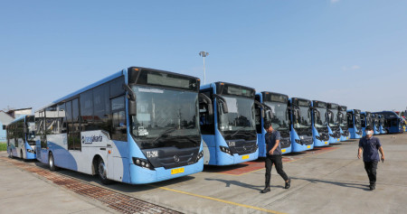 Pekerja melintas di dekat deretan bus TransJakarta di Jakarta, Sabtu (27/8/2022). Bisnis/Himawan L Nugraha