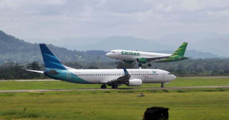 Pesawat Citilink (atas) saat akan mendarat dan pesawat Garuda Indonesia yang akan lepas landas di Bandara Sultan Hasanuddin Makassar, Sulawesi Selatan, Senin (18/2/2019). / Bisnis-Paulus Tandi Bone