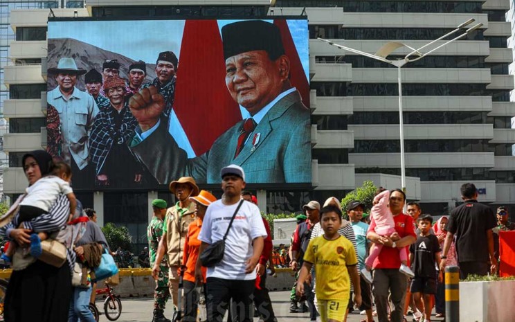 Warga melintas di jalan jendral Sudirman menjelang pelantikan Presiden Terpilih Prabowo Subianto dan Wakil Presiden Terpilih Gibran Rakabuming Raka di Jakarta, Minggu (20/10/2024). Bisnis - Abdurachman