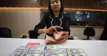 Karyawan memperlihatkan Rupiah dan dolar AS di salah satu tempat penukaran uang asing di Jakarta, Senin (21/10/2024)./ JIBI/Bisnis/Eusebio Chrysnamurti