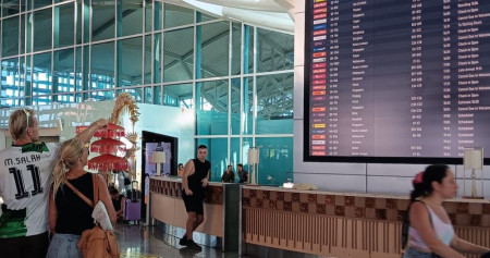 Turis manca negara memperhatikan papan jadwal penerbangan di Bandara Ngurah Rai Bali, Kamis (14/11/2024)./Bisnis - Harian Noris Saputra.