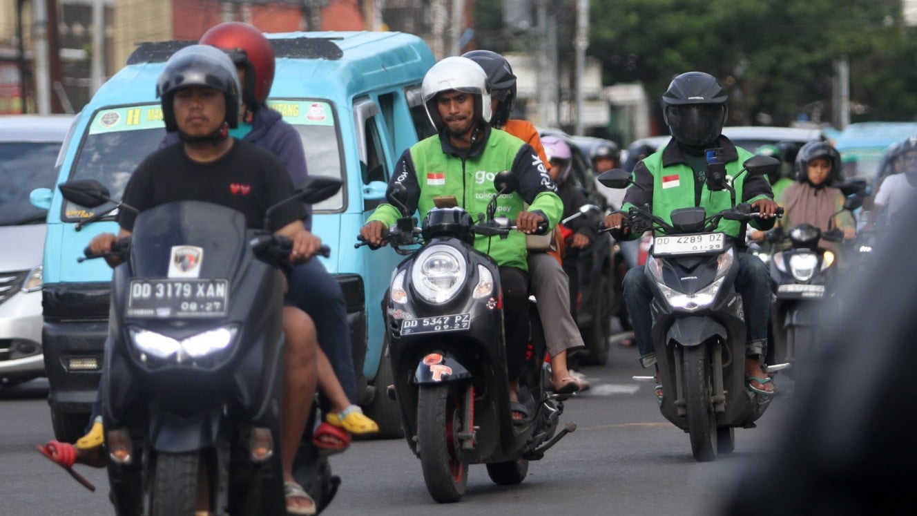 Driver Gojek mengantarkan penumpang dan pesanan makanan di Makassar, Sulawesi Selatan, Selasa (11/3/2025). /Bisnis/Paulus Tandi Bone