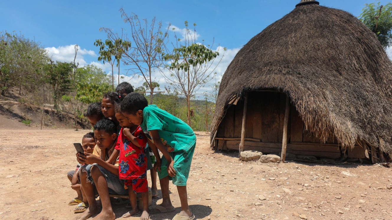 Anak-anak Suku Boti mengakses smartphone di depan Ume Kbubu atau rumah bulat di Desa Boti, Timor Tengah Selatan, Nusa Tenggara Timur (NTT), Minggu (26/11/2023)./Bisnis/Himawan L Nugraha