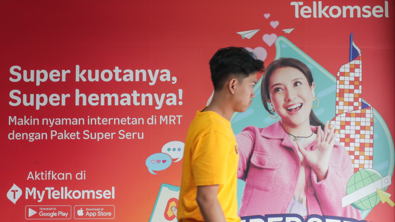 Warga melintas di dekat logo PT Telekomunikasi Selular (Telkomsel) di Jakarta, Minggu (9/3/2025)./Bisnis/Fanny Kusumawardhani