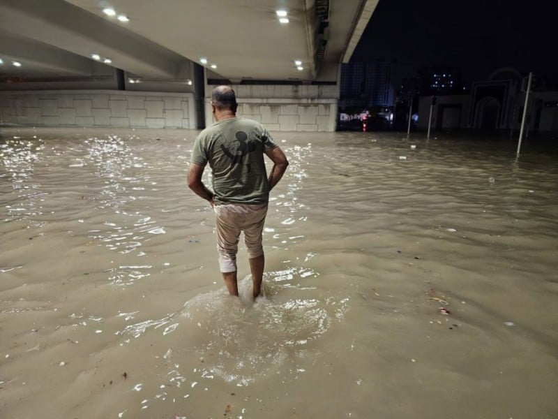 Orang-orang menyeberang melalui jalan yang terendam di bawah jembatan setelah hujan lebat di Uni Emirat Arab pada 16 April 2024./Reuters/Anadolu