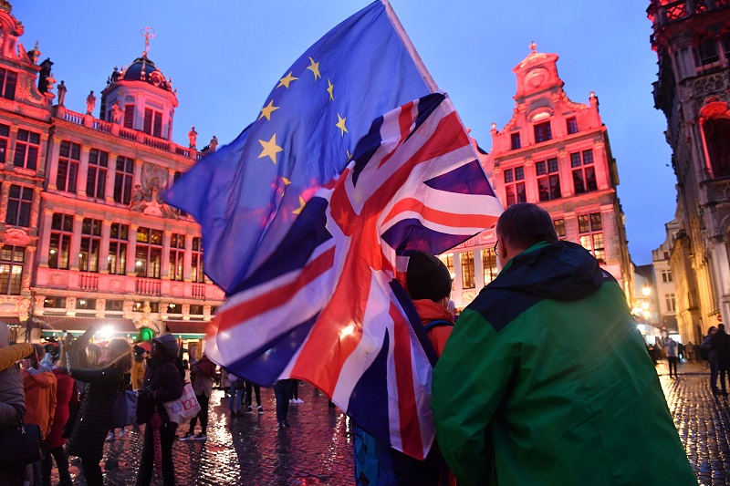 Pejalan kaki mengibarkan bendera UE dan Inggris di Brussels pada 30 Januari 2020/Bloomberg