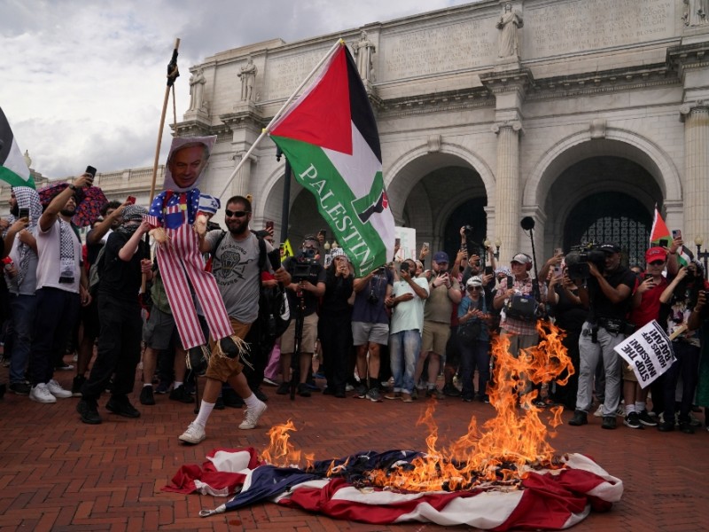 Bendera AS terbakar saat seorang demonstran pro-Palestina memegang patung Perdana Menteri Israel Benjamin Netanyahu, di luar Union Station,pada hari Perdana Menteri Israel Benjamin Netanyahu menyampaikan pidato dalam pertemuan gabungan Kongres Amerika Serikat di Capitol Hill, Washington, Rabu (24/7/2024)./Reuters-Natan Howard