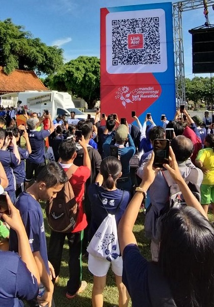 Pengunjung area festival Mandiri Banyuwangi Half Marathon 2019 sedang melakukan snap QR untuk memenangkan doorprize yang disediakan di Taman Blambangan Banyuwangi, Minggu (31/3). Metode undian dengan metode snap QR ini merupakan yang pertama kali dilakukan sekaligus untuk mendorong penggunaan aplikasi LinkAja oleh Masyarakat.