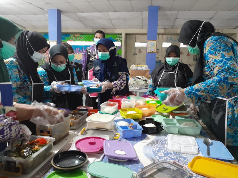 Para guru dan staf SMPN 2 Curug, Tangerang mempersiapkan makanan dalam simulasi program Makan Siang Gratis. - Bisnis/Annasa_Rizki