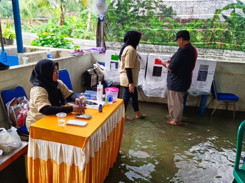 Warga menggunakan hak suaranya dalam Pemilu 2024 di Tangerang kendati TPS tampak digenangi air/Dok.-Bisnis