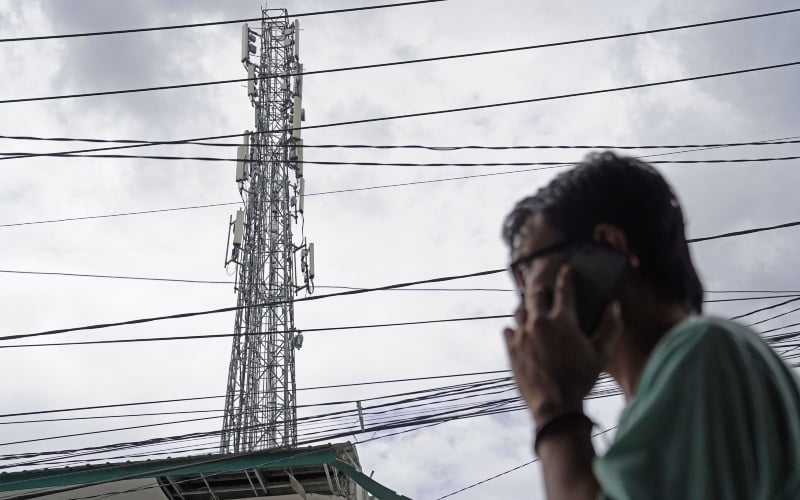 Warga menelpon di dekat menara telekomunikasi. Aktivitas menelpon dapat terjadi berkat dukungan spektrum frekuensi