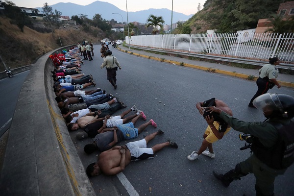 Orang-orang yang ditahan oleh pasukan keamanan berbaring di jalan/Reuters