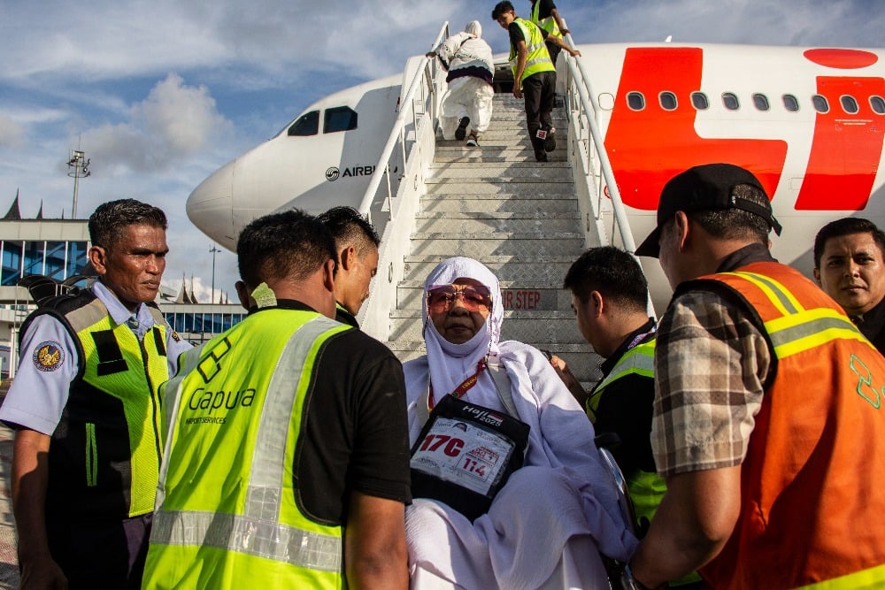 Petugas melayani jemaah calon haji berusia lansia dengan cara digotong ketika hendak memasuki pesawat Lion Air di Bandara Internasional Minangkabau (BIM), Kabupaten Padang Pariaman, Sumatra Barat, Sabtu (3/5/2025). Bisnis/Muhammad Noli Hendra