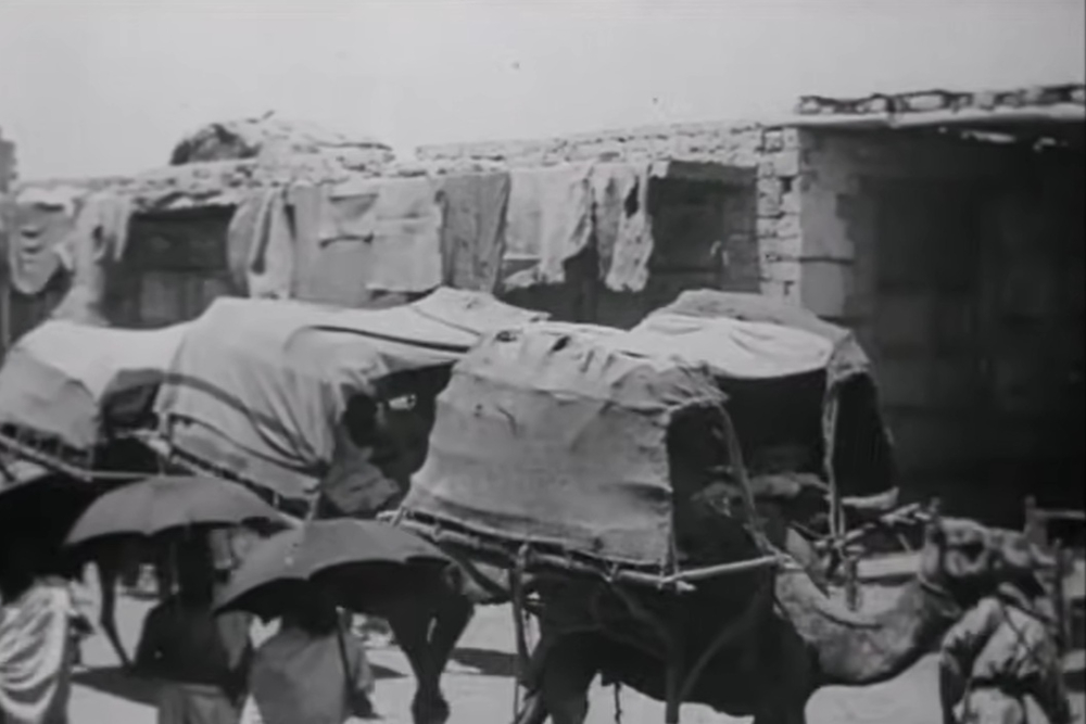Perjalanan jemaah haji Nusantara dari Jeddah menuju Makkah menggunakan karavan unta, dari tangkapan layar film bisu Pilgrimage to Mecca, 1928, karya G. Kruggers. /youtube.com/@tvculture