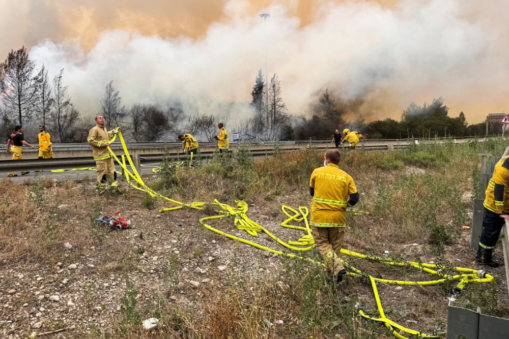 Petugas pemadam kebakaran Israel bekerja di dekat Latrun saat kebakaran hutan akibat panas ekstrem dan angin melanda Israel bagian tengah pada 30 April. REUTERS/Sinan Abu Mayzer